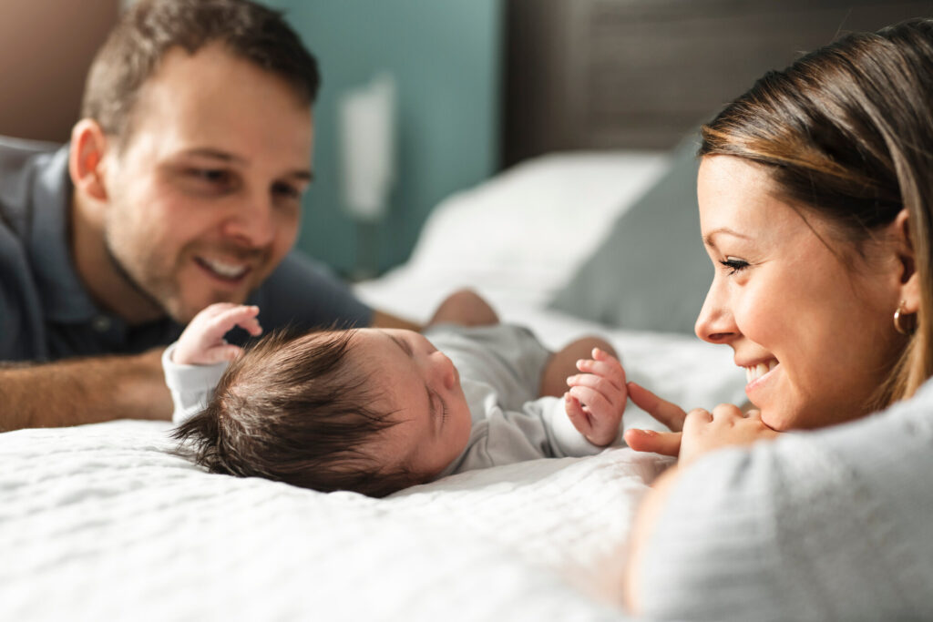 Ein schönes Paar mit neugeborenem Baby im Bett.