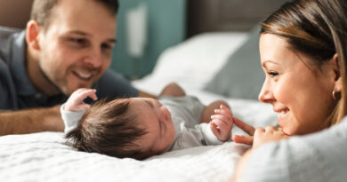 Ein schönes Paar mit neugeborenem Baby im Bett.