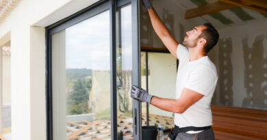 junger Mann beim Einbau eines Erkerfensters auf einer Baustelle für ein neues Haus