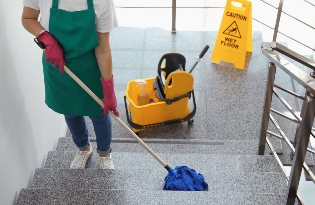 Junge Frau mit Wischmopp beim Treppenputzen