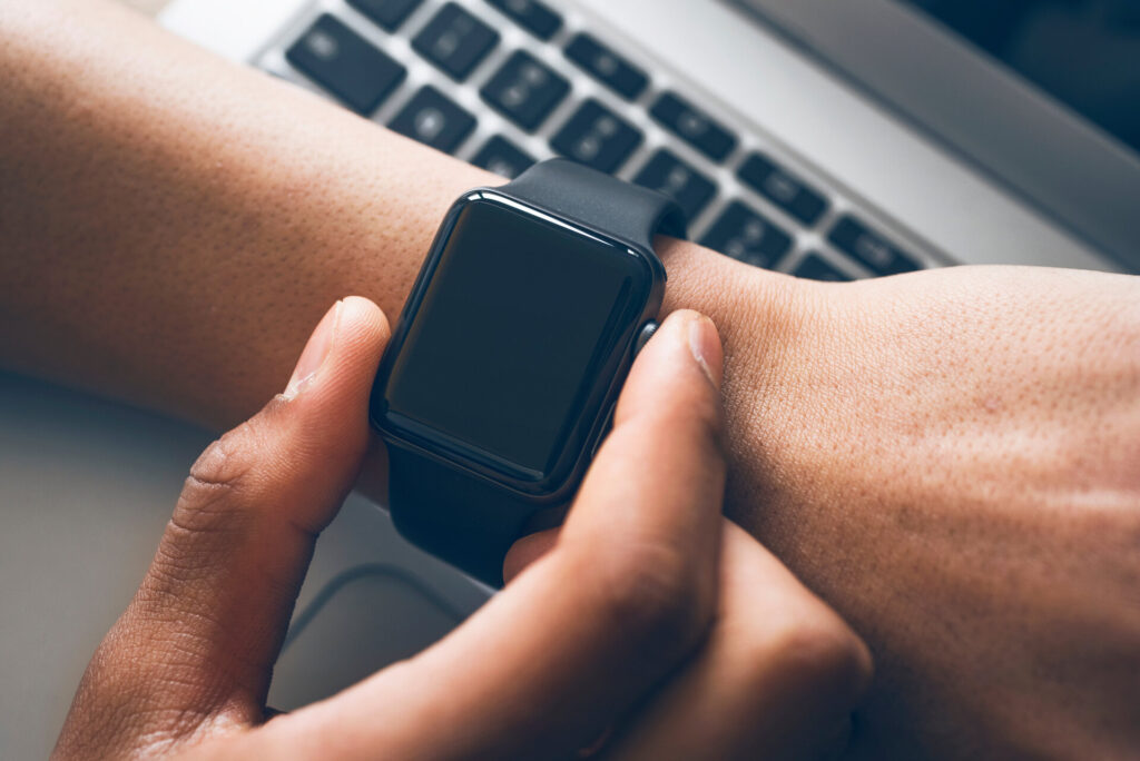 Person trägt eine Smartwatch am Handgelenk und überprüft die Uhrzeit oder Benachrichtigungen. Das Bild zeigt die Integration von Technologie in den Alltag und die Nutzung von Smartwatches zur Steigerung der Effizienz.