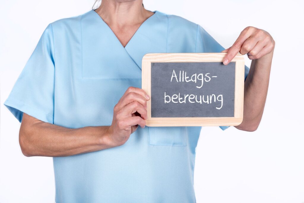 Pflegehilfskraft zeigt Tafel mit der Aufschrift "Alltagsbetreuung"