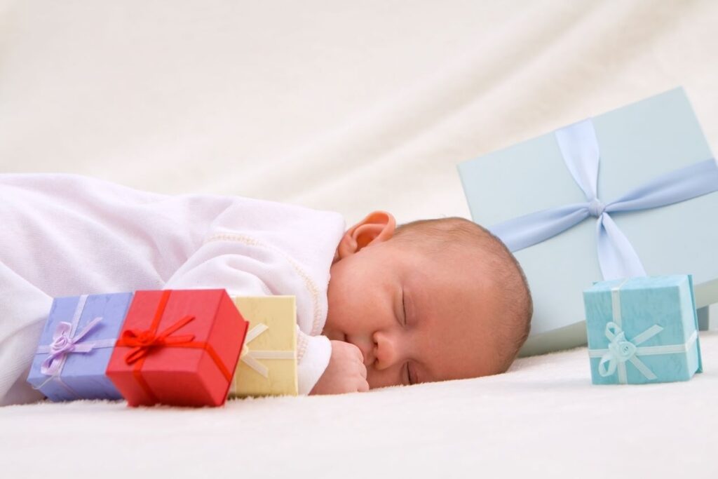 Ein schlafendes Baby mit bunten Geschenkboxen – Babygeschenk Inspiration für frischgebackene Eltern