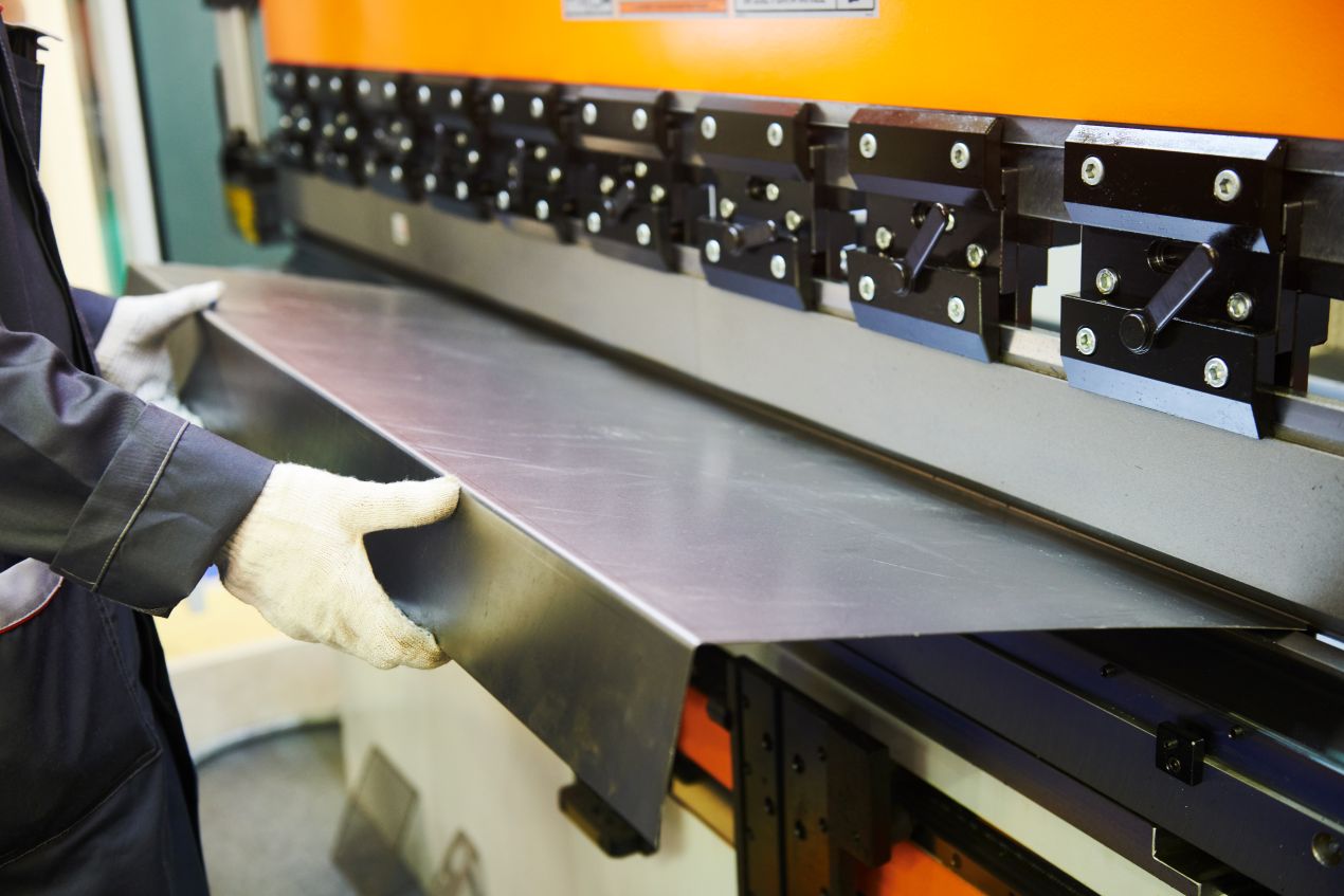 Mitarbeiter arbeitet an gebrauchter Biegemaschine in moderner Werkstatt bei praeziser Blechbearbeitung