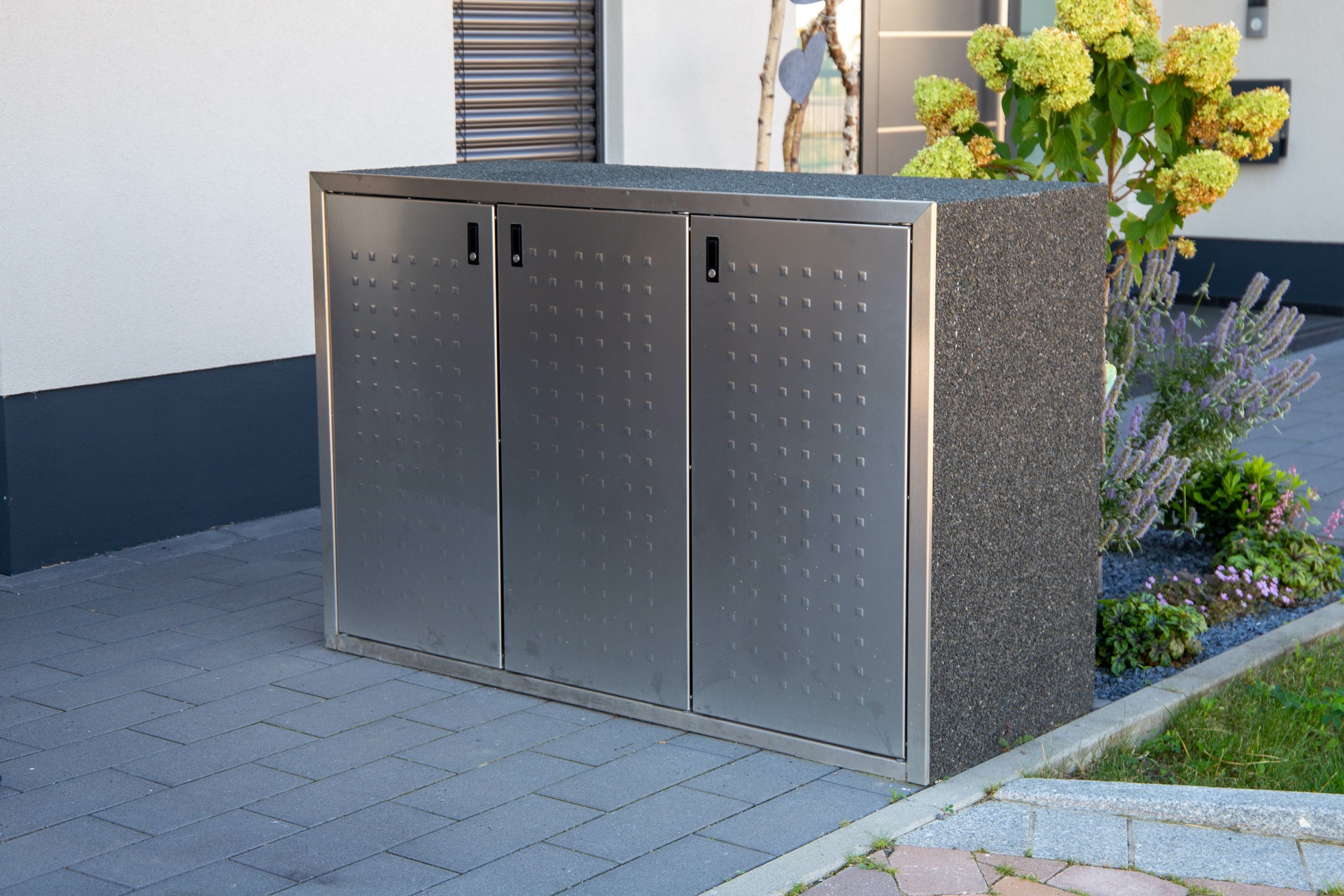 Edelstahl-Muelltonnenbox auf grauem Pflaster