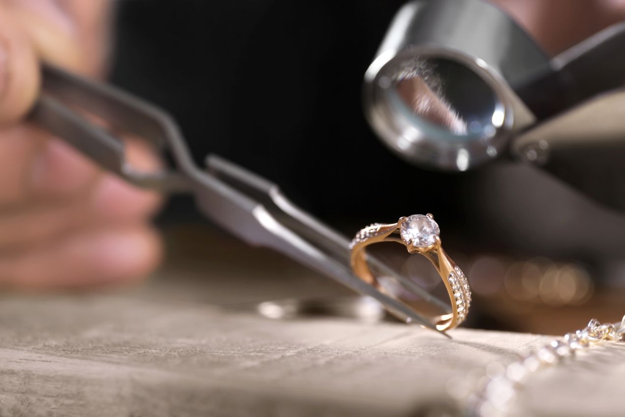 goldschmied betrachtet eheringe aus silber unter einer lupe