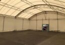 Innenansicht eines großen Lagerzelts mit Stahlträgern und lichtdurchlässiger Plane, ideal für flexible Lagerlösungen