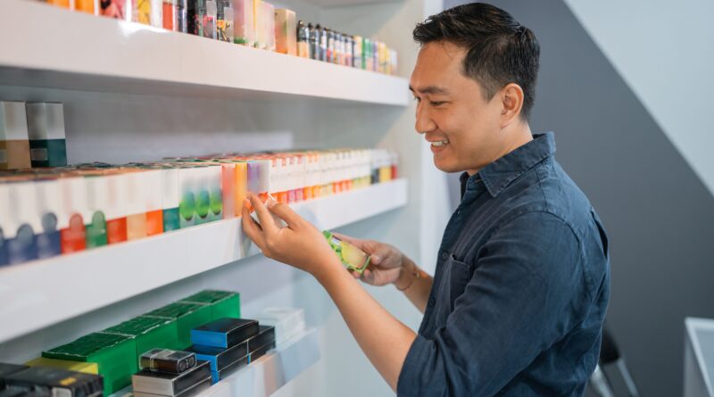Mann prüft Elfbar Liquids im Fachhandel und vergleicht verschiedene Geschmacksrichtungen im Regal