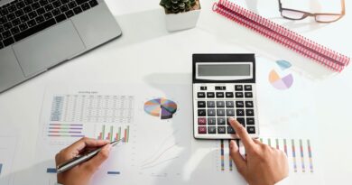 Person arbeitet mit Taschenrechner und Finanzunterlagen am Schreibtisch | Rechnungsblöcke