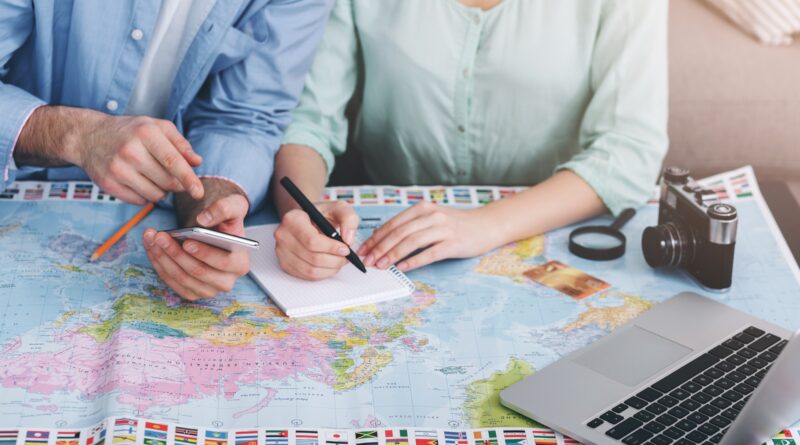Paar plant Reise mit Weltkarte und Laptop | Emirates Business Class