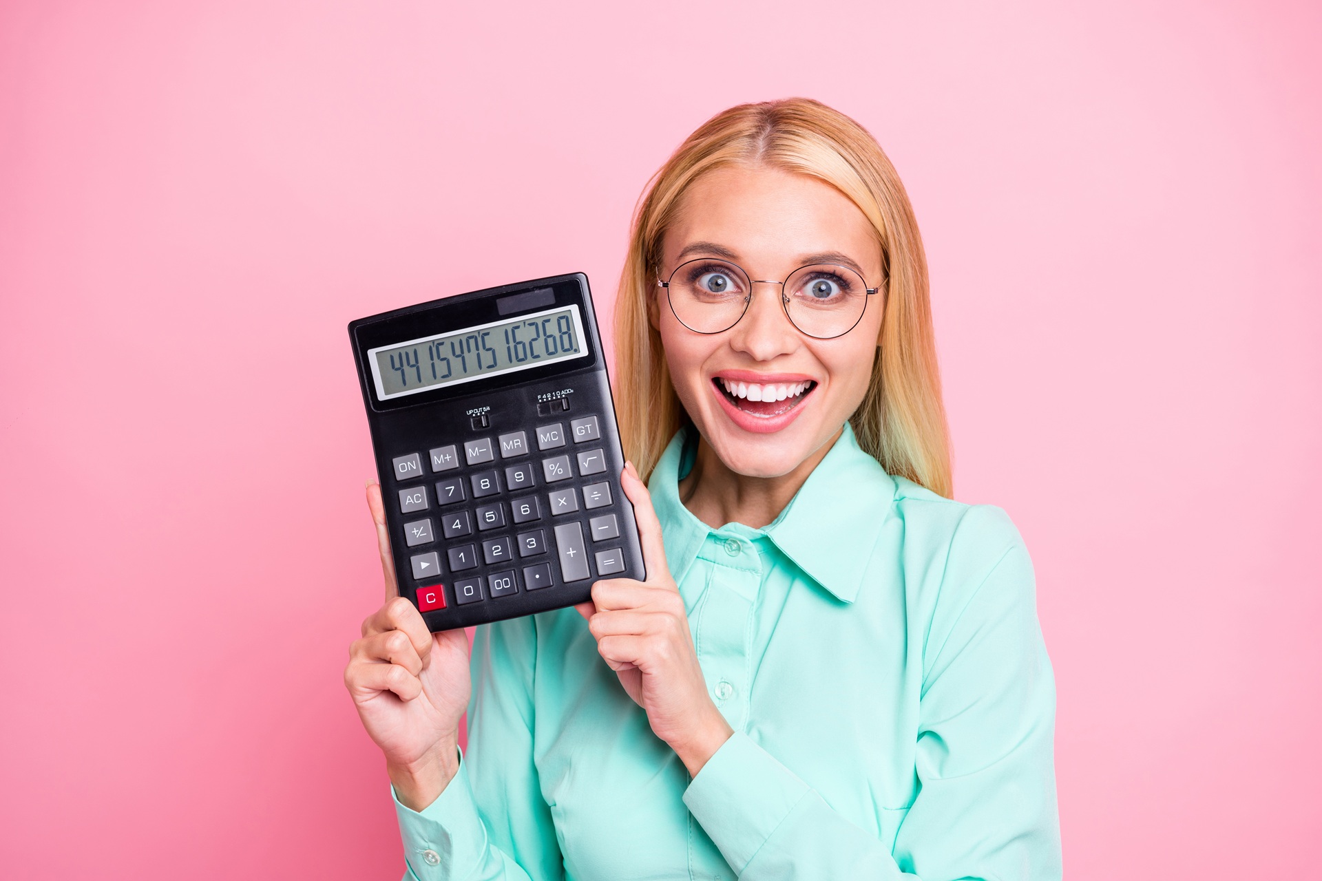 Lächelnde Frau hält großen Taschenrechner vor rosa Hintergrund | Rechnungsblöcke