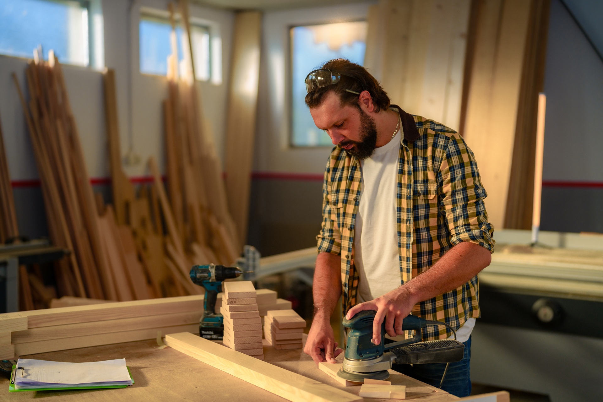 Schreiner schleift Holz in seiner hellen Werkstatt | Schreiner-Software